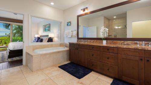 a bathroom with a tub and a large mirror at TROPICAL BREEZES Stunning Views from KaMilo 3BR Home Walk to Beach in Waikoloa