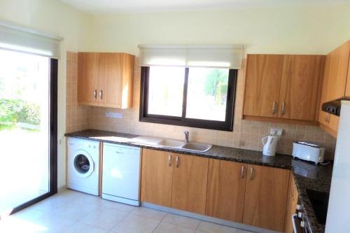 a kitchen with a sink and a washing machine at Modern 3 bedroom villa, pool and close to golf course in Paphos City