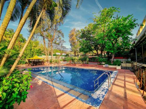 a swimming pool in a yard with trees at Zaras Resort Khandala in Lonavala