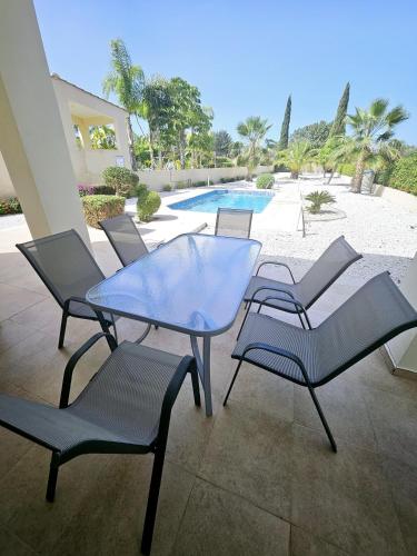 a patio with a table and chairs and a pool at Modern 3 bedroom villa, pool and close to golf course in Paphos City