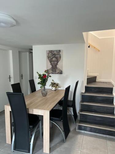 une salle à manger avec une table en bois et des chaises noires dans l'établissement Maison spacieuse proche Paris, à Bonneuil-sur-Marne