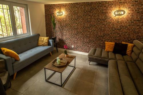 a living room with two couches and a brick wall at Maison spacieuse proche Paris in Bonneuil-sur-Marne