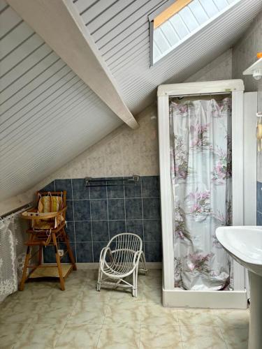 La salle de bains est pourvue d'un lavabo, d'une chaise et d'une douche. dans l'établissement Gîte 4 personnes vue sur le lac des graves - Vallée de la Jordanne,Aurillac,Cantal,Auvergne, à Lascelle