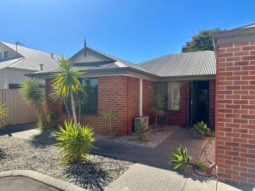 a brick house with a palm tree in front of it at South Bunbury Holiday Home in Carey Park