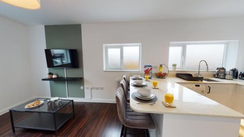 Stylish Duplex Apartment with Home Office في نيوبورت: مطبخ مع طاولة مع كراسي وقمة كونتر