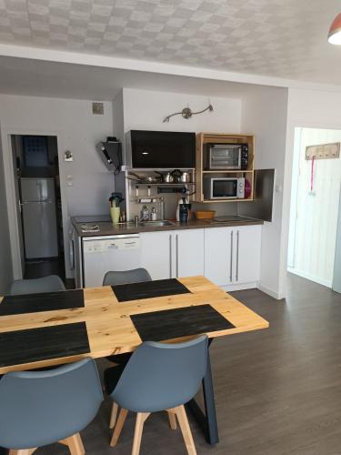 une cuisine avec une table en bois et des chaises bleues dans l'établissement Appartement cosy en résidence, avec parking, à Saint-Hilaire-de-Riez