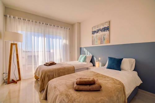 a bedroom with two beds and a window at Luxury Penthouse Alcazaba Lagoon 521 EHHouse in Estepona