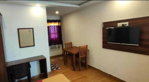 um quarto com uma mesa e uma televisão na parede em Hotel New Cresent park em Coimbatore