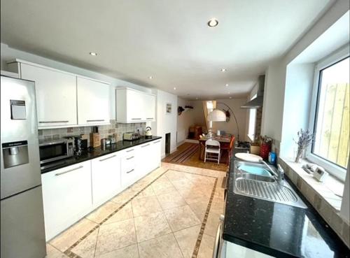 a large kitchen with white cabinets and a table at *Family Home in Mumbles. Close to the Beach* in The Mumbles