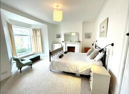 Dormitorio blanco con cama y chimenea en *Family Home in Mumbles. Close to the Beach*, en Mumbles