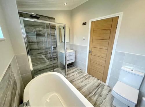 a bathroom with a tub and a toilet and a shower at *Luxury holiday home with hot tub close to beach* in Pembrokeshire