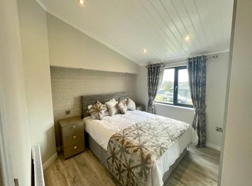 a bedroom with a bed with pillows and a window at *Luxury holiday home with hot tub close to beach* in Pembrokeshire