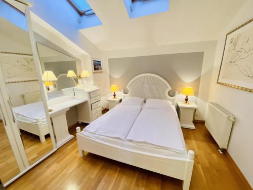 Schlafzimmer mit einem weißen Bett und einem Spiegel in der Unterkunft Sonnenaufgang, direkt am Alten Strom in Warnemünde