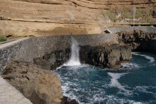 a waterfall on a cliff with water rushing through it at Hotel Costa Linda in Porto da Cruz