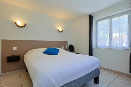 a bedroom with a bed with a blue pillow on it at Logis Hotel l'Esterella in Agay - Saint Raphael