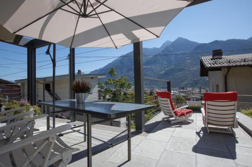 un patio con mesa, sillas y sombrilla en Alpinetouch, en Aosta