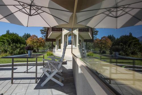 un patio avec deux tables, deux chaises et des parasols dans l'établissement Alpinetouch, à Aoste