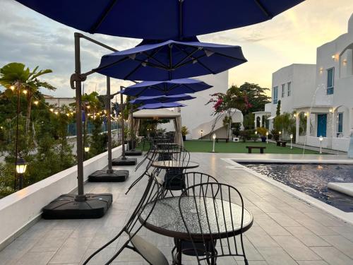 a row of tables and chairs with blue umbrellas at The Arjana Resort in Masjid Tanah