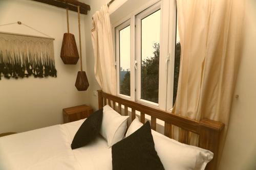 um quarto com uma cama com almofadas e uma janela em KACHINS Homes em Coonoor