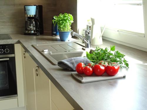 a kitchen counter with tomatoes on a cutting board next to a sink at Gode Wind Quartiere 1 in Dahme