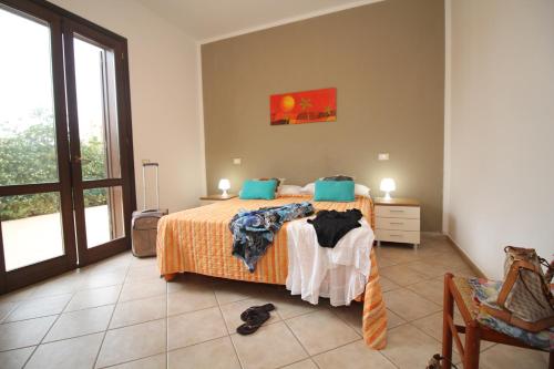 a bedroom with a bed with orange sheets and blue pillows at 9 Nereide in San Vito lo Capo