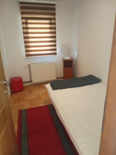 a bedroom with a bed and a window with a fan at GuestHouse in Sarajevo