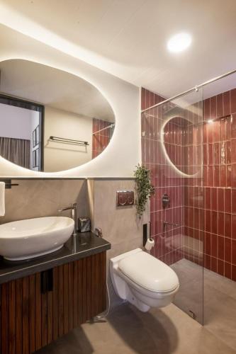 a bathroom with a toilet and a sink and a mirror at 3BHK Villa With Private Pool & Concierge in Asagao in Assagao