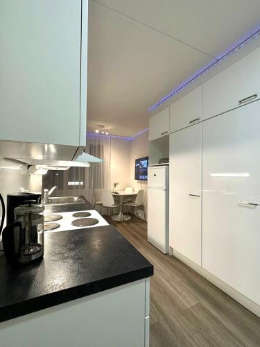 eine Küche mit weißen Schränken und einer schwarzen Arbeitsplatte in der Unterkunft Cozy studio apartment in Helsinki