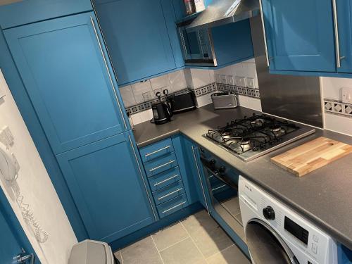 La cuisine est équipée de placards bleus et d'un four avec plaques de cuisson. dans l'établissement Immaculate 2-Bed Apartment in London, à Londres