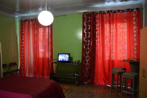 a bedroom with red curtains and a tv in it at Green House in Genoa