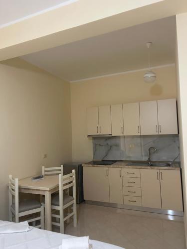 a kitchen with white cabinets and a table and chairs at Rest House in Vlorë