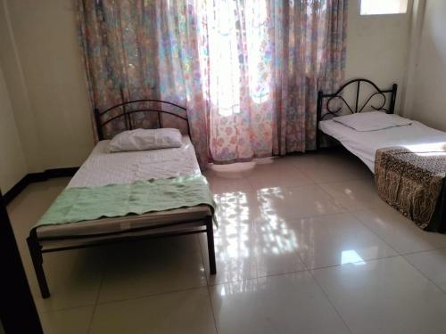 a small room with two beds and a window at THE TAJ Inn in Cagayan de Oro