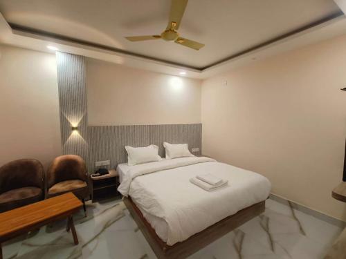 una camera con un letto bianco e una sedia di Hotel GD Grand Inn a Gorakhpur