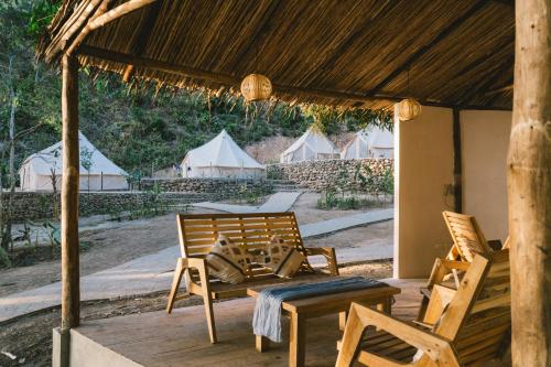 um alpendre com duas cadeiras, um banco e tendas em Parada Beach Camp em El Nido