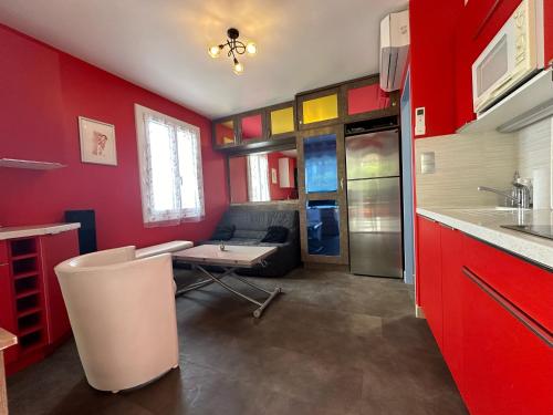 - une cuisine avec des murs rouges, une table et un canapé dans l'établissement Village naturiste - Port-Vénus - Villa Betty Boop, au Cap d'Agde