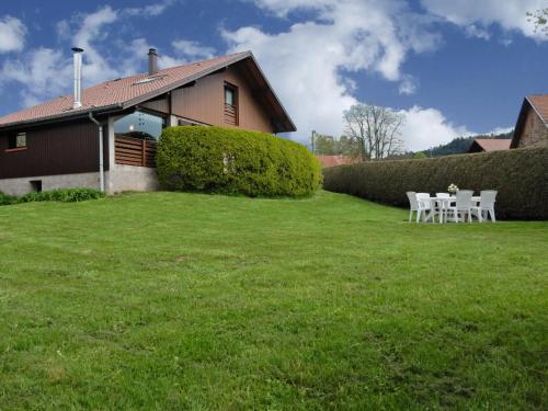 a yard with two white chairs and a house at Elegant Chalet in Gerb pal in cosy environment in Gerbépal