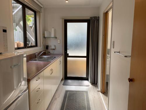 uma cozinha com uma porta que leva a uma cozinha com um lavatório em Wakatipu View Apartments em Queenstown