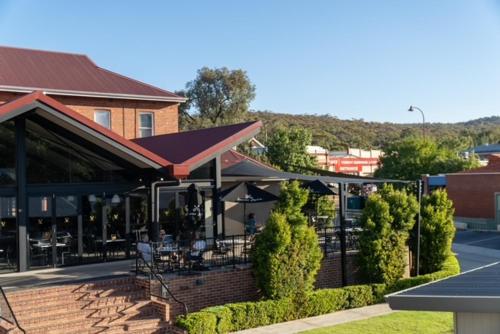 ein Gebäude mit einer Terrasse mit Tischen und Stühlen in der Unterkunft Victoria Hotel Toodyay in Toodyay