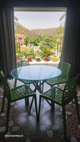 una mesa de cristal y sillas con vistas a un patio en Corbett Wala Home Stay, en Rāmnagar