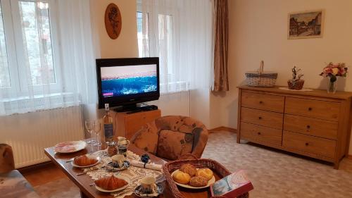 a living room with a television and a table with food at Modrá růže Třeboň in Třeboň