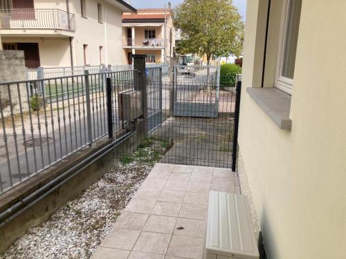 um banco sentado ao lado de uma varanda com uma cerca em Appartamento a 200 mt dal mare em Lido di Jesolo