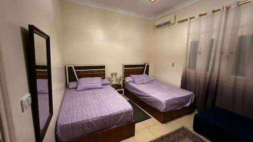 two beds in a small room with purple sheets at فيلا توين هاوس مميزة في قرية رويال بيتش رأس الحكمة villa twin house Royal Beach Ras El Hekma in Marsa Matruh