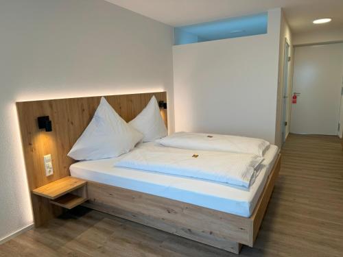 Bett mit einem Kopfteil aus Holz in einem Zimmer in der Unterkunft MEIN MOTEL - Self Check-in 