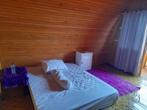- une chambre avec un lit blanc et un mur en bois dans l'établissement Pondok Wisata Botu Barani, à Gorontalo