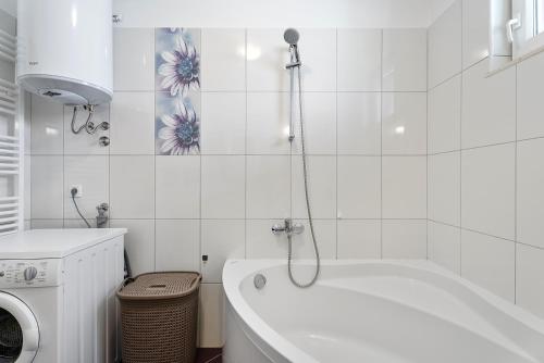 a white bathroom with a tub and a washing machine at Modern apartment with private pool near Split in Podstrana
