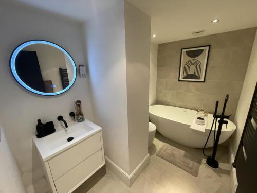 La salle de bains est pourvue d'une baignoire, de toilettes et d'un miroir. dans l'établissement Immaculate 2-Bed Apartment in London, à Londres