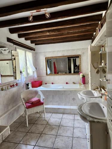 une grande salle de bain avec une baignoire et un lavabo dans l'établissement Maison normande avec piscine chauffée privée, à La Croupte