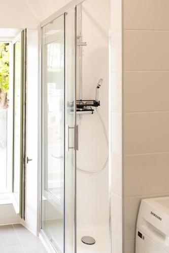 une douche avec une porte vitrée dans une salle de bain dans l'établissement Les Maisons de l'Abreuvoir Côté Village, à Marly-le-Roi