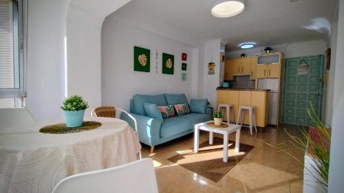 un soggiorno con divano blu e una cucina di Hoja Calá Apartment a Algarrobo-Costa
