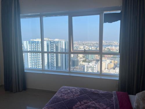 una camera da letto con finestra affacciata sulla città di fantastic city & Seaview Master bedroom in 3bedroom apartment ad Ajman